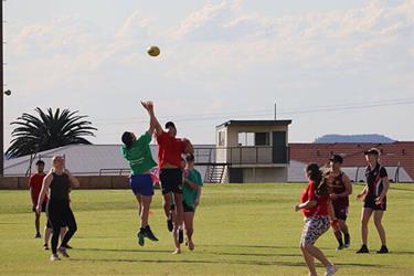 A group of Residential Colleges residence playing football on an oval.