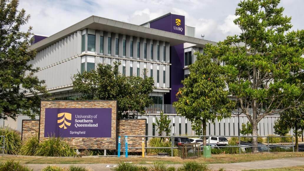 Modern building with University of Southern Queensland signs, surrounded by trees and greenery at the Springfield campus.