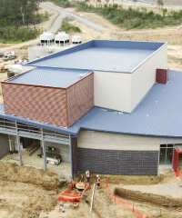 Aerial view of the auditorium building at UniSQ Springfield campus under construction with workers and construction equipment visible around the site.