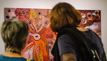 Two people looking at a painting.