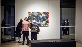 People looking at a painting in a art gallery.