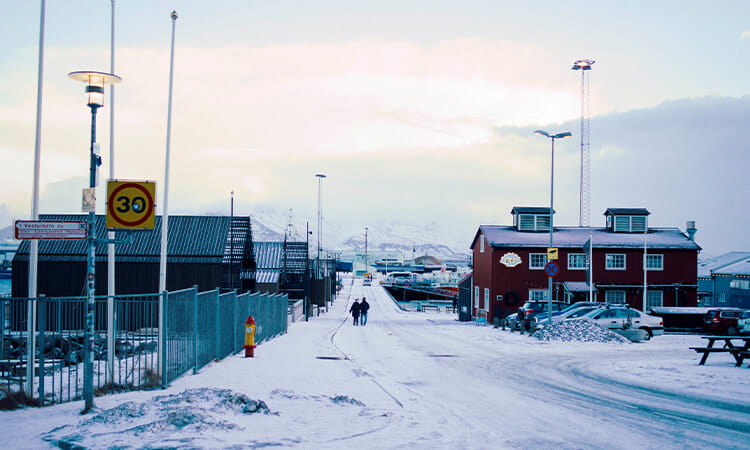 Two people walking in an isolated town covered in snow.