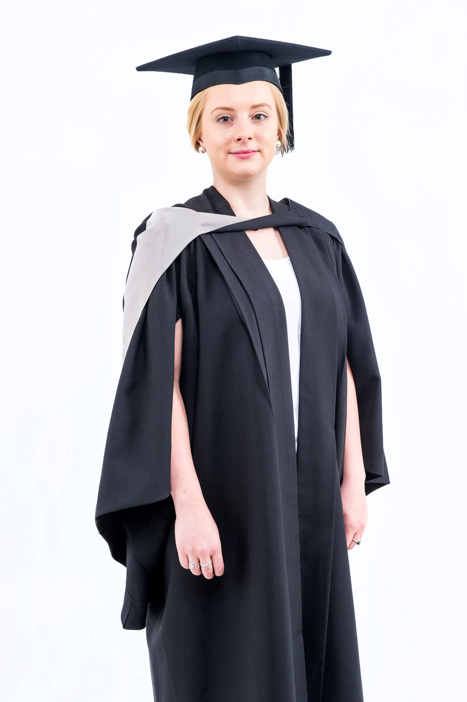 A woman in a graduation cap and gown standing against a white background.