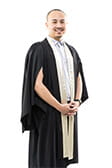 Man in graduation attire smiling against a white background.