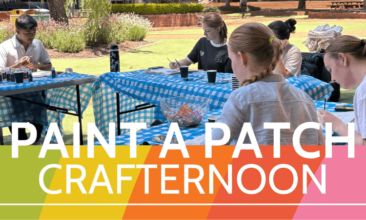A group of people sit at outdoor tables covered with blue checkered cloths, painting and crafting. Text reads "PAINT A PATCH CRAFTERNOON" over a rainbow banner.
