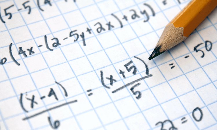 A yellow pencil rests on a sheet of graph paper with handwritten algebraic equations and fractions.