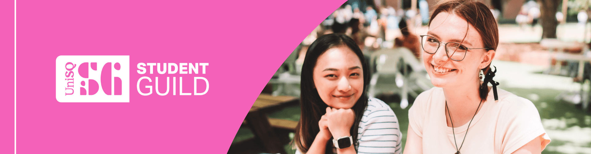 Two students sitting at an outdoor table, smiling at the camera. The left side features a pink banner with the UniSQ Student Guild logo and text.