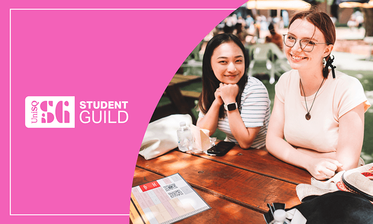 Two students sit at an outdoor table smiling, with notebooks and drinks in front of them. UniSQ Student Guild branding is displayed on a pink background to the left.