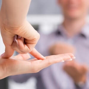 Two people communicate using sign language, with one person’s hands visible in the foreground signing on their palm.