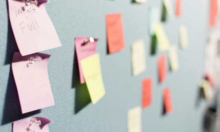 Sticky notes of various colors are pinned to a wall, some with handwritten text.