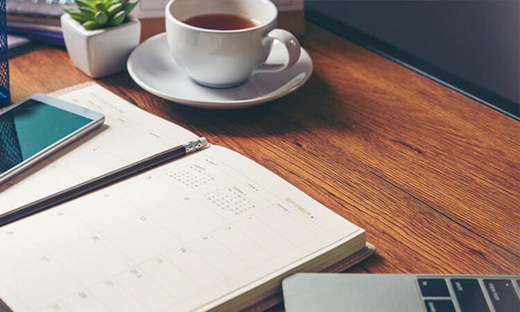 desk with coffee, notepad and laptop