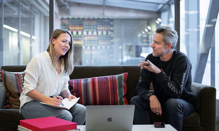 Two professionals having a discussion in a modern office setting.