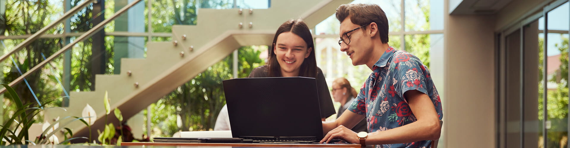 Two male students sitting at a laptop in the UniSQ Ipswich Library.
