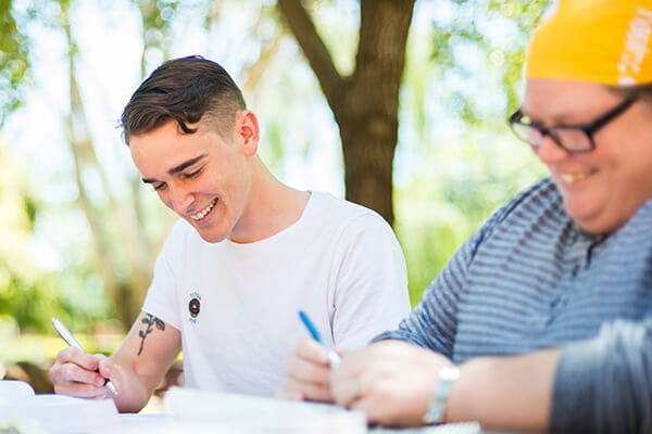 Two students sitting outdoors smiling