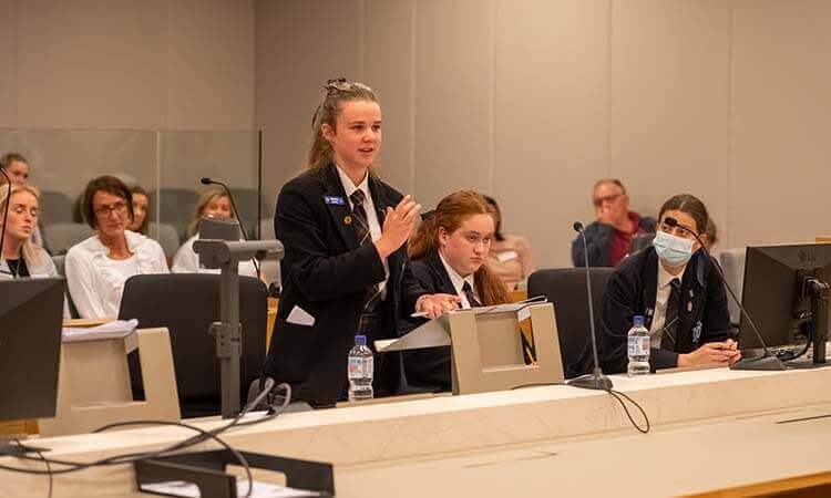 A group of people sitting at a desk in a courtroom.