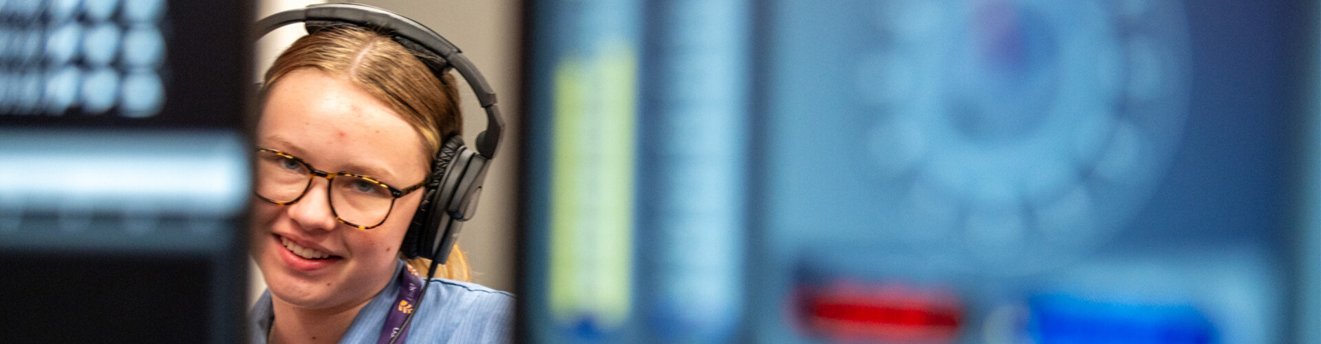 A focused professional wearing a headset in front of computer monitors.