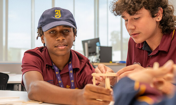 Two students engaged in a classroom activity, constructing a project with wooden pieces.