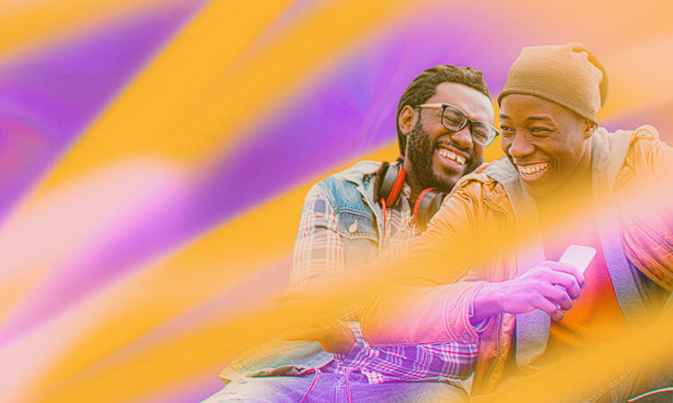 Two people smile and laugh while sitting together, with vibrant orange and purple stripes surrounding them. One person holds a smartphone, and both are casually dressed.