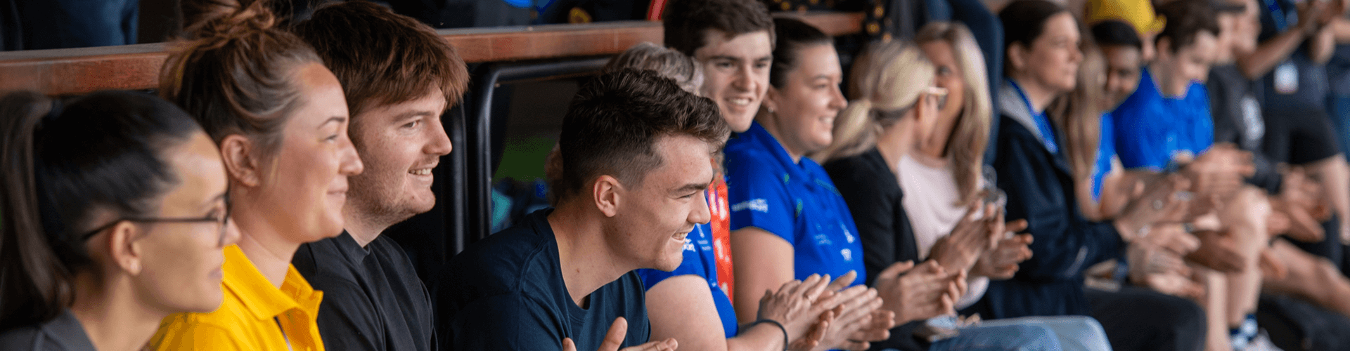 A group of people clapping in a stadium.