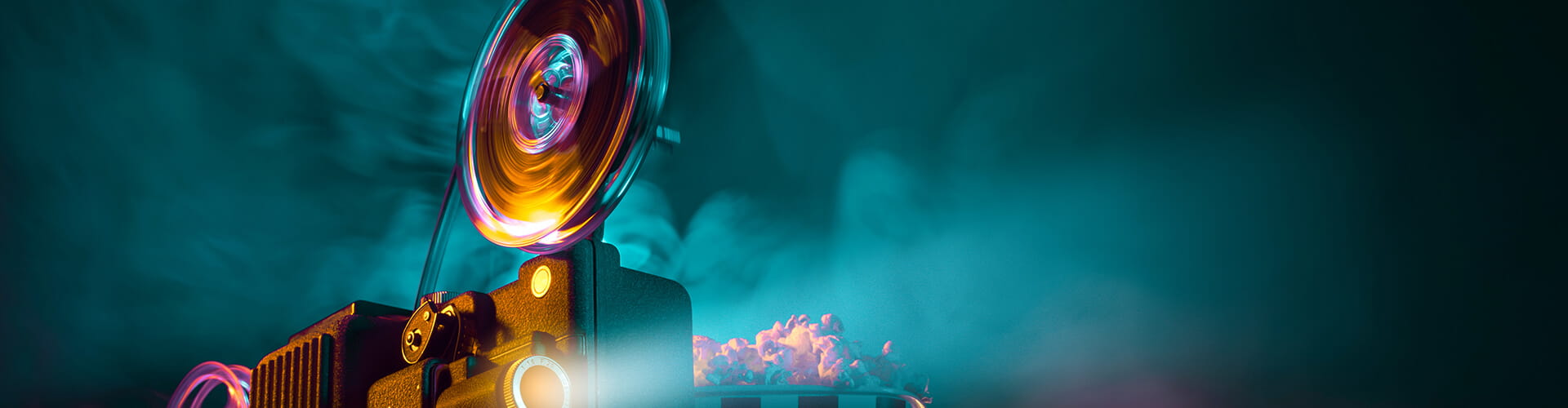 A vintage film projector emitting light and smoke with a tub of popcorn nearby.