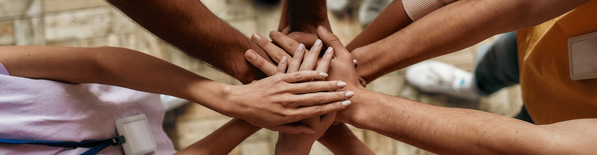 A group of diverse hands stacked together in a symbol of teamwork and unity.