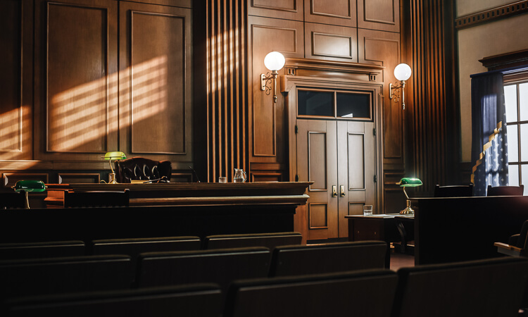 Empty courtroom with wooden benches, judge’s bench, and sunlight streaming through windows, highlighting the formal, classic interior design.