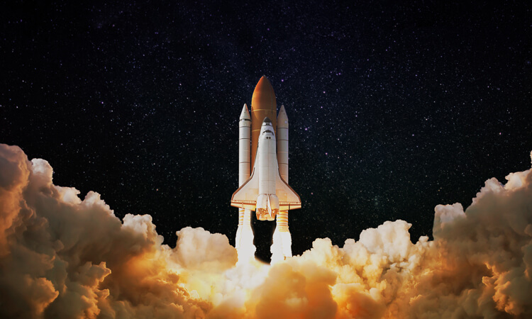 A space shuttle launches into the night sky, surrounded by clouds of smoke and fire, with stars visible in the background.