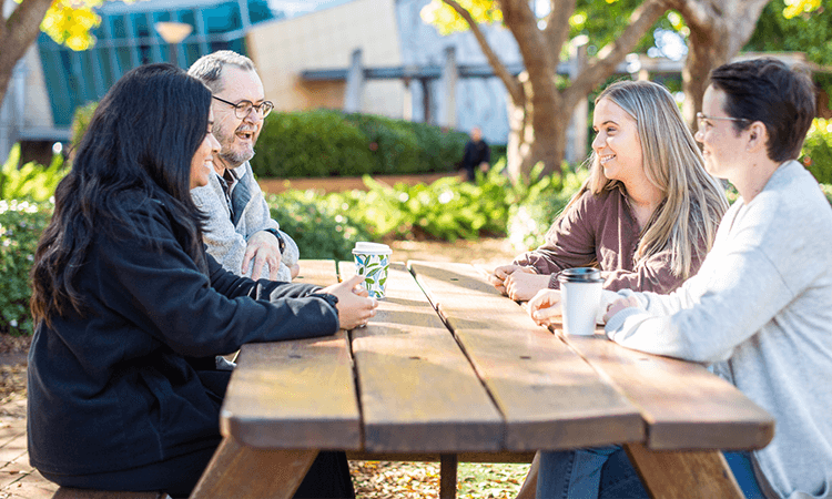 Students sitting and speaking at a park table