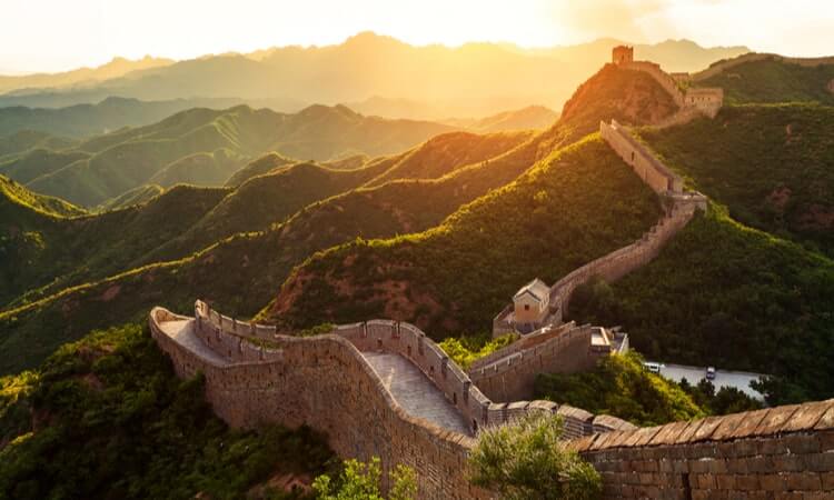 Great Wall of China winding through mountainous landscape at sunset.