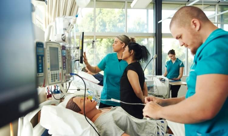 UniSQ nursing students monitoring a patient in a simulated hospital room.