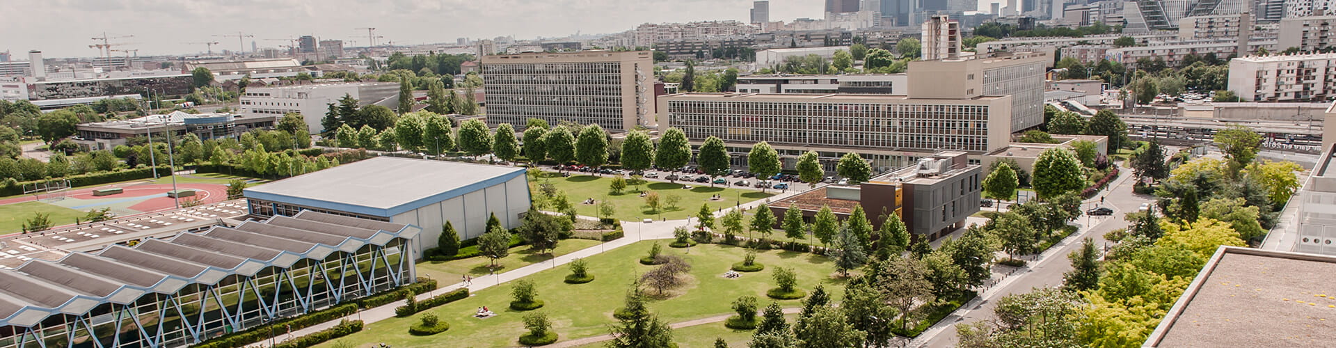 Aerial view of a modern urban campus with green spaces, buildings, and a running track.