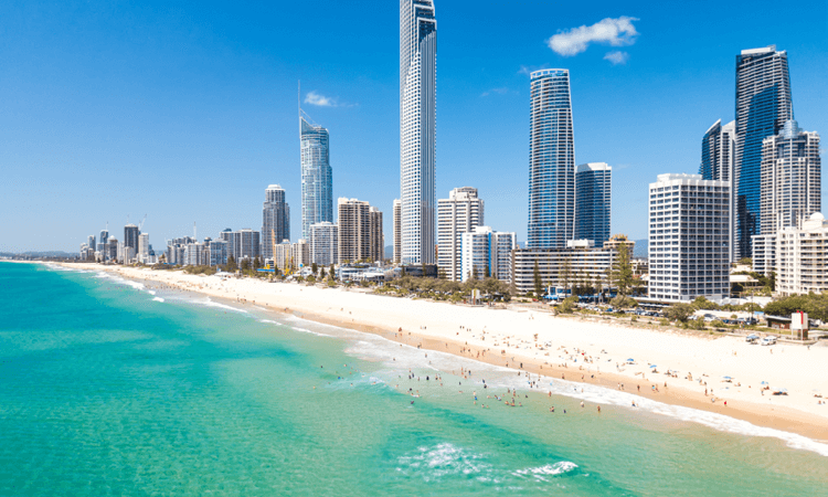 Coastal cityscape with skyscrapers adjacent to a crowded beach on a sunny day.