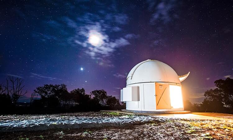Observatory under a starlit sky with a bright moon.