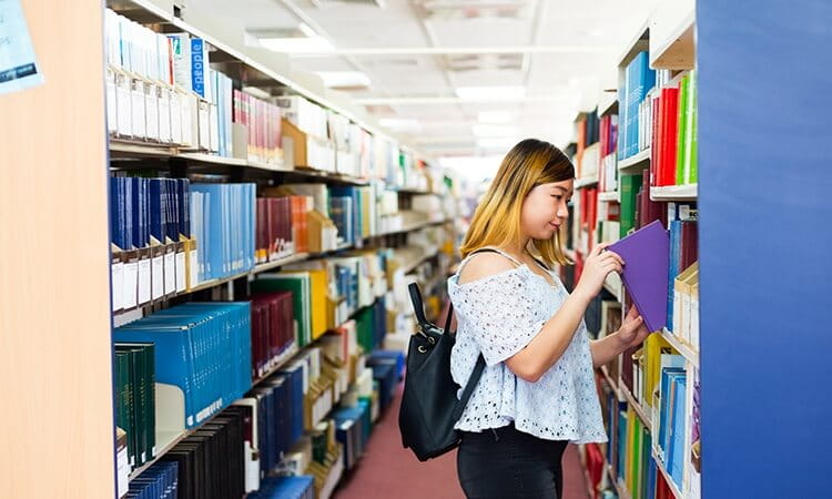 A student search the library shelves for a book