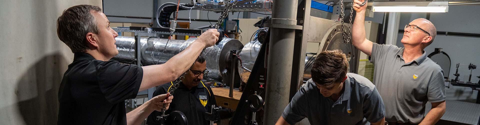 Four people next to hypersonic wind tunnel