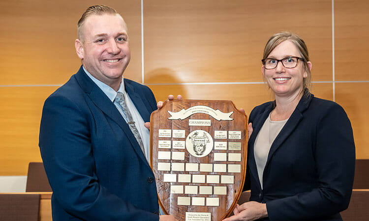 Two people holding trophy shield