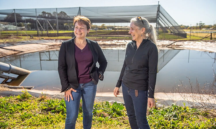 two woman in front of a dam smiling