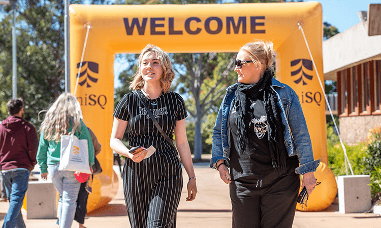 people walking under welcome sign