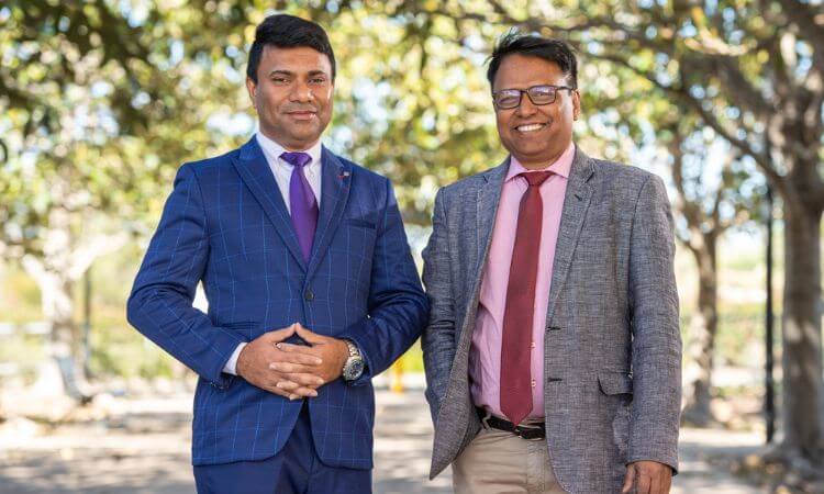 two men in suits smiling 