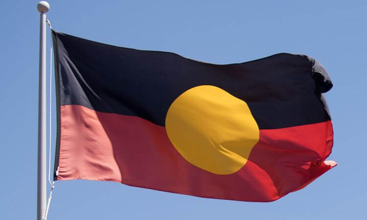 The aboriginal australian flag waving against a clear blue sky.