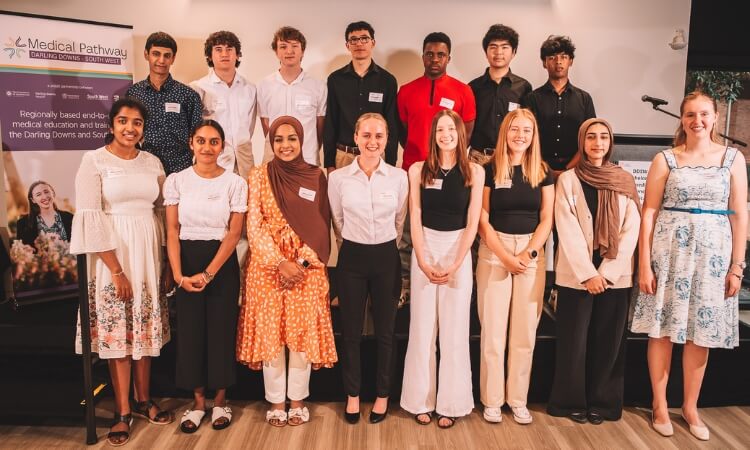 Group of students posing for a photo at a medical pathway event, standing in front of a banner.