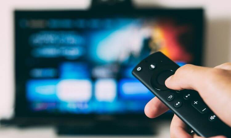 Person using a remote control to navigate a smart tv interface.