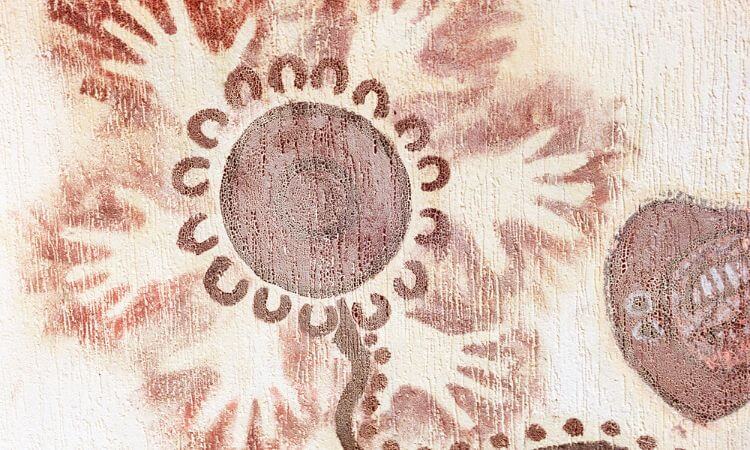 A wall painting depicting a large, stylized sunflower with a circular center and radiating petals in shades of brown and beige.