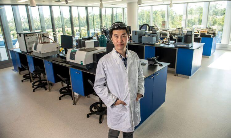 A person in a lab coat stands in a modern laboratory with various scientific equipment and workstations.