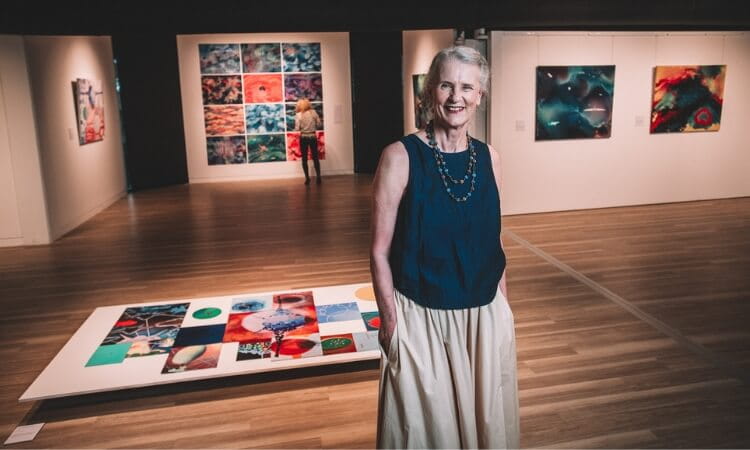 A person standing in a modern art gallery, with colorful abstract artworks on the walls and floor.