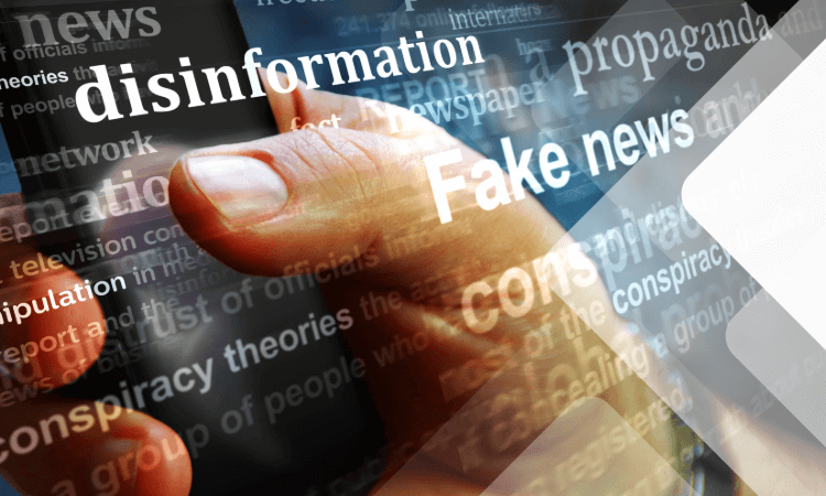 A hand holding a smartphone with overlaid words like "disinformation," "Fake news," and "propaganda" symbolizing misinformation in media.