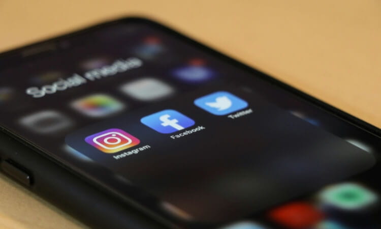 Close-up of a smartphone screen displaying a folder labeled "Social media" with Instagram, Facebook, and Twitter app icons visible.