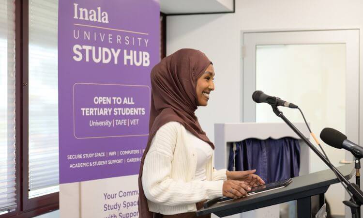 A woman in a hijab speaks at a podium near a sign for Inala University Study Hub, which offers services to tertiary students.