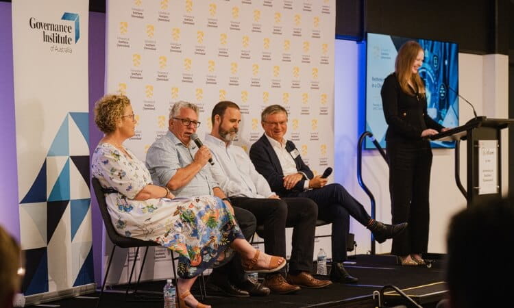 Four panelists are seated and speaking into microphones while a woman stands at a podium during a Governance Institute of Australia event.