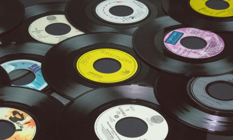 A collection of vintage vinyl records with various colored center labels scattered on a flat surface.